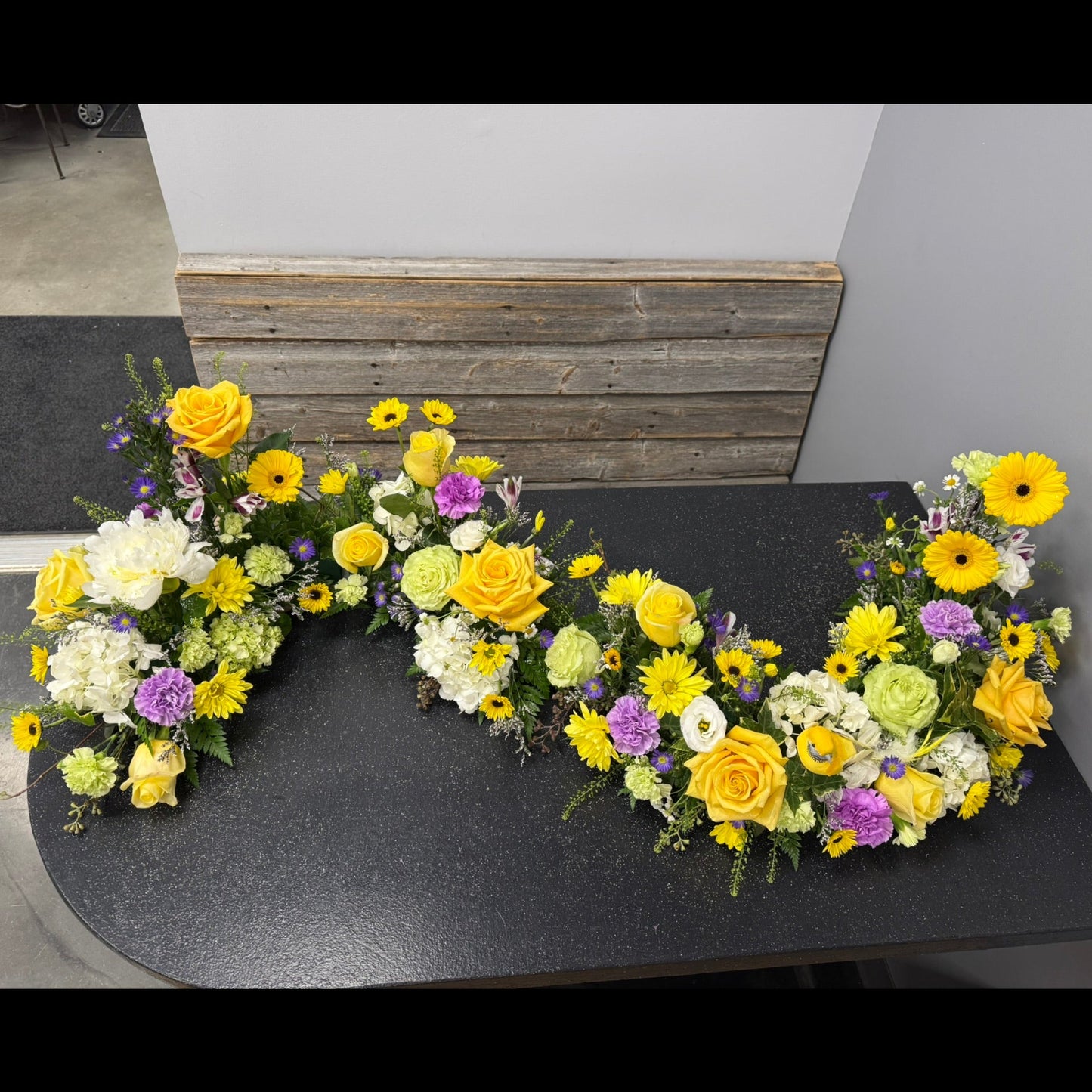 Decorative floral arrangement shaped like a heart on a black surface.