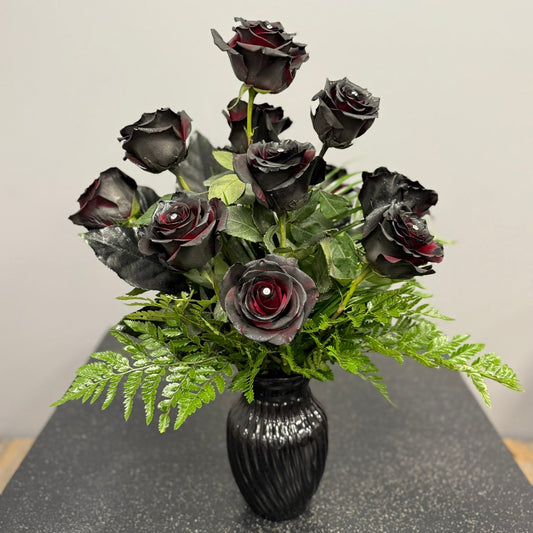 Bouquet of black roses in a black vase on a gray surface with a light gray background
