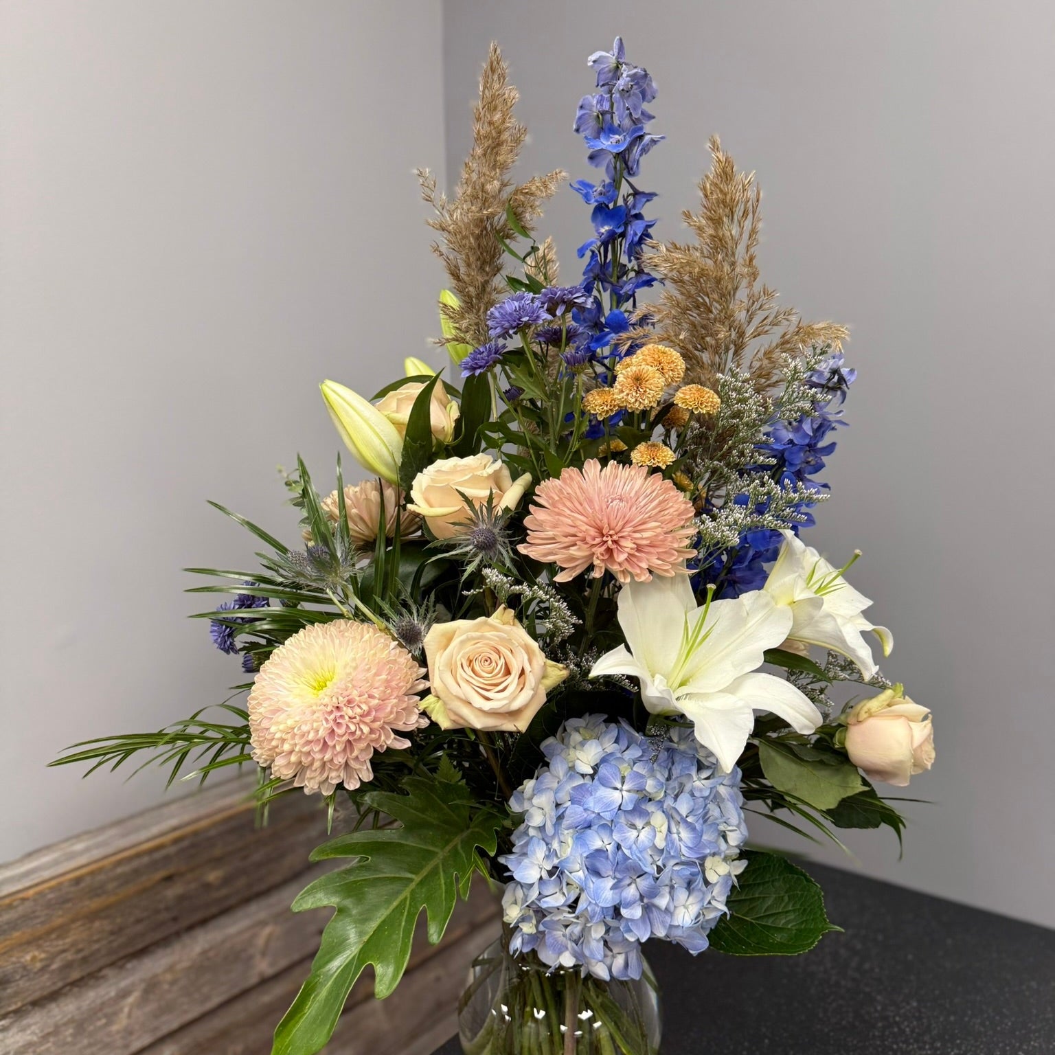 Bouquet of flowers in a clear vase on a dark surface with a gray background