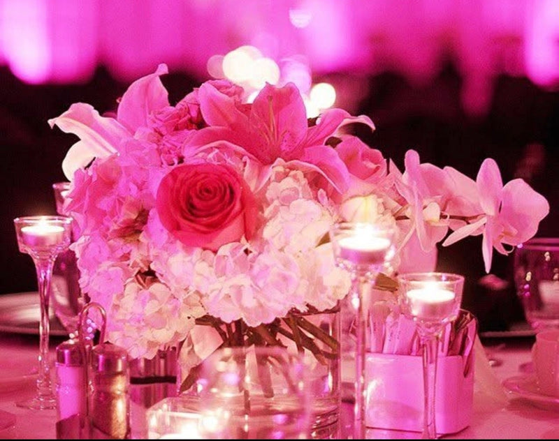 Pink floral arrangement with candles on a table against a pink backdrop