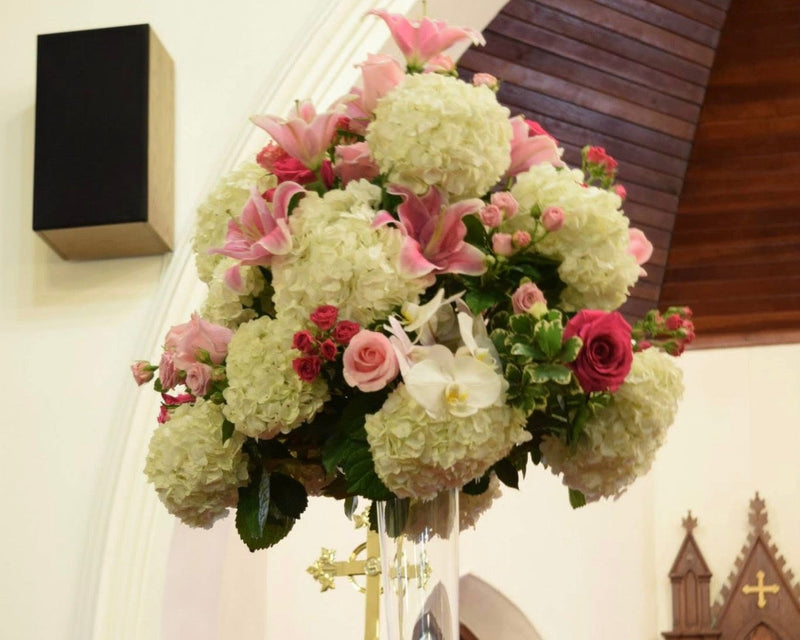Decorative floral arrangement in a church setting with stained glass windows and wooden architecture.