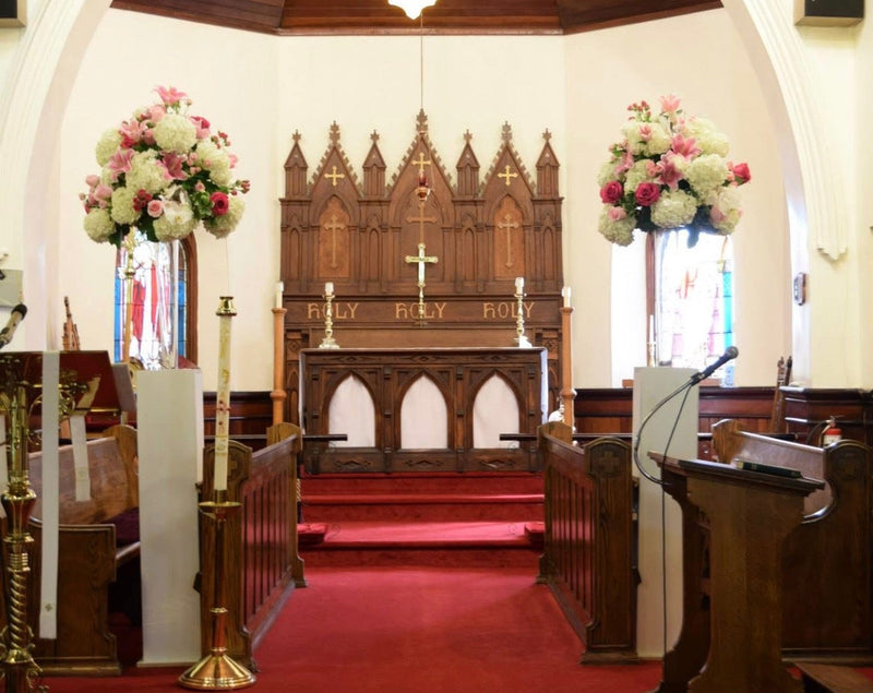 Nave of a church with pews, altar, and floral arrangements.