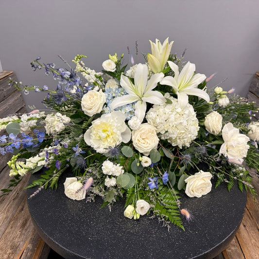 Floral arrangement with white and green flowers on a dark surface.