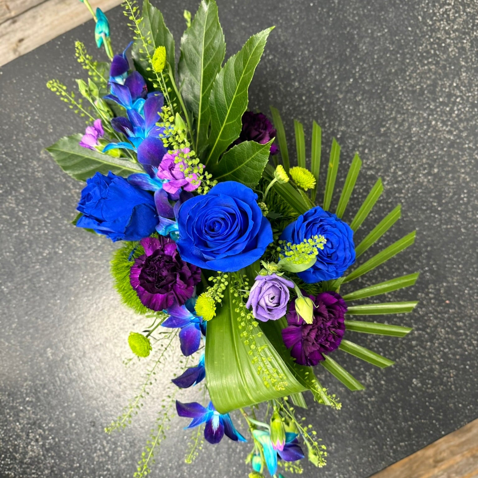 Bouquet of blue and purple flowers on a dark surface