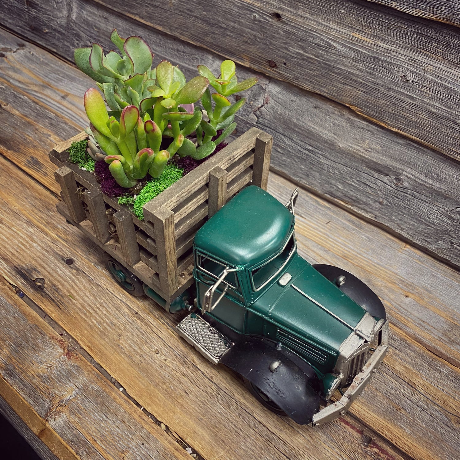 antique green work truck with a wooden cargo box filled with a succulent planter