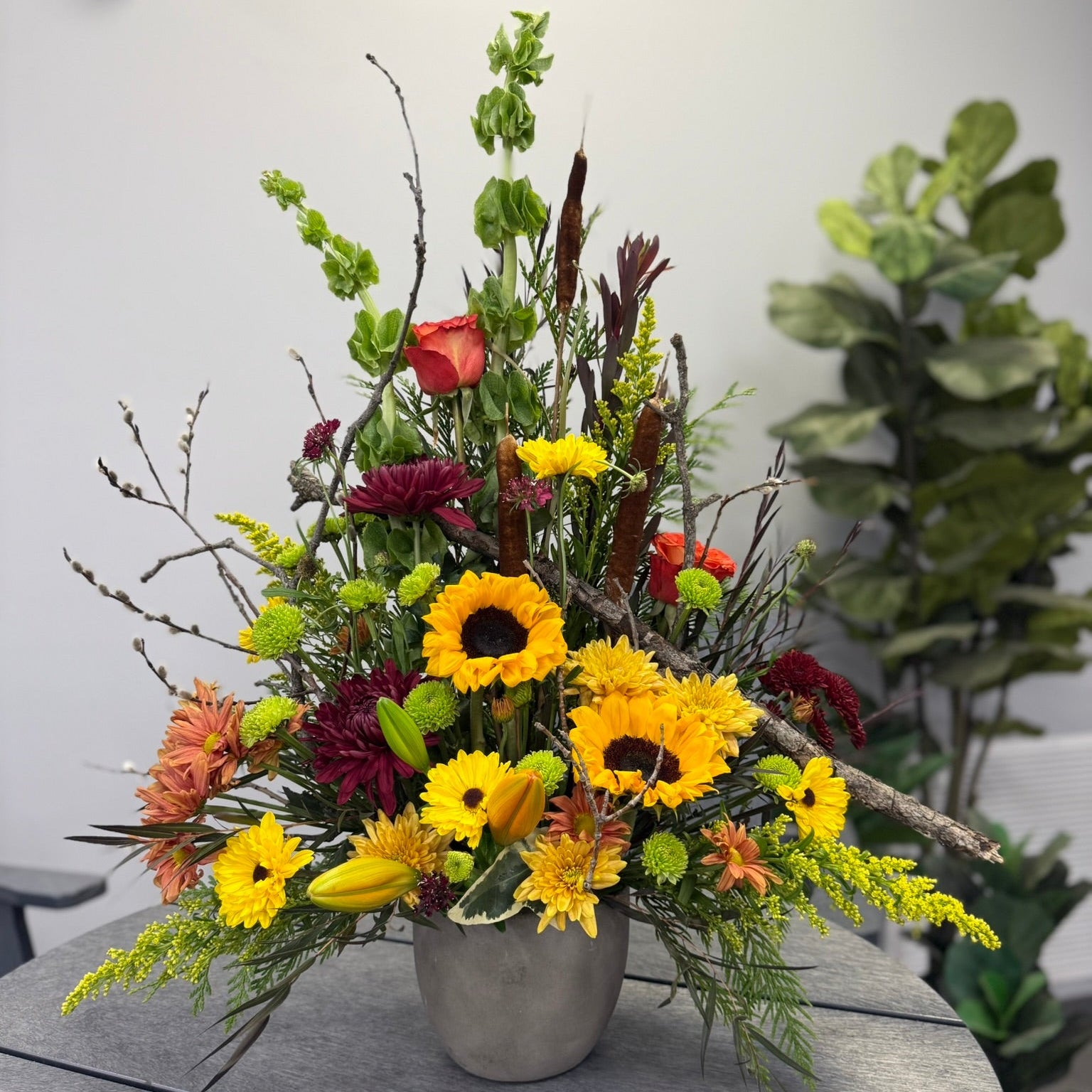 Bouquet of flowers with sunflowers and other assorted flowers in a vase on a table.